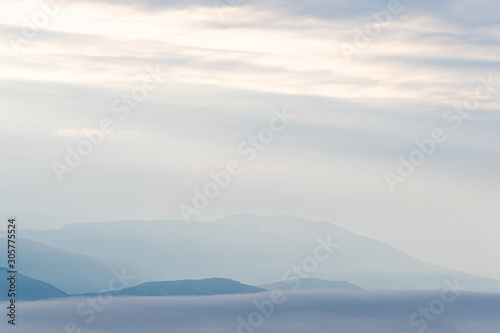 Gentle hills in bluish haze. Soft light in early morning, silhouettes of mountains