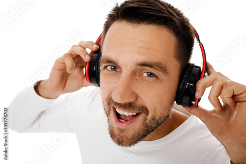 Close-up portrait of handsome bearded young man in headphones listening to music and dancing isolated on white background.