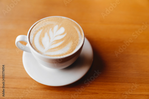 Top view of hot coffee cappuccino cup with milk foam on wood table background