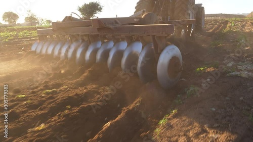 Close-up cropped rear view of the plough discs on the back of a tractor ploughing fields on a large scale farm