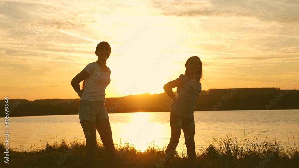 happy girls dancing on the beach. party by lake, children dancing. beautiful girls having fun listening to music. sisters are dancing. teens girlfriends holiday disco.