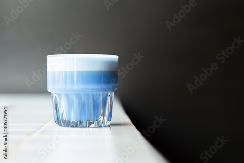  Blue latte with coconut cream white tile on a black background. Blue match latte in a glass isolated on white background, clipping path included. Hot coffee. A place for copywriting