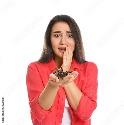Scared young woman with tarantula on white background. Arachnophobia  fear of spiders 