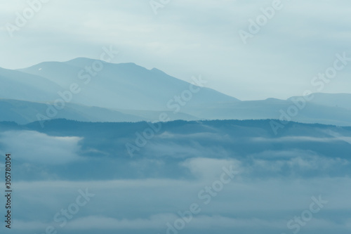 Gentle hills in bluish haze. Soft light in early morning, silhouettes of mountains