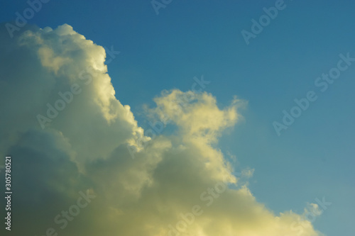 a storm cloud lit by the sun in a blue sky