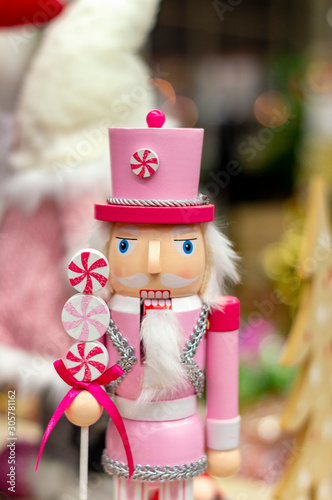Pink nutcracker man, wooden Christmas toy on  store shelf.