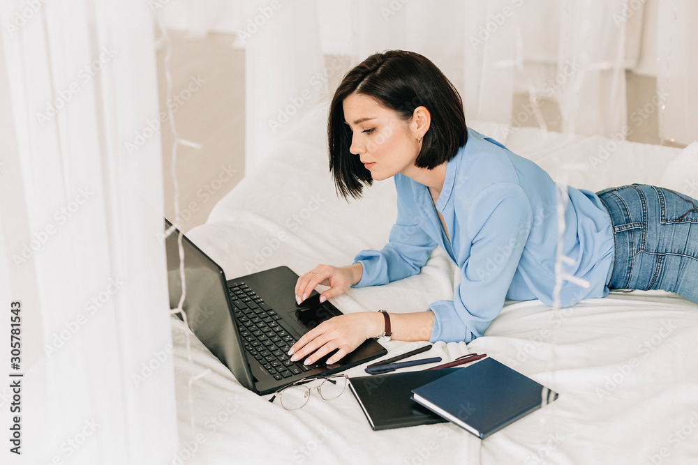 Businesswoman working on her laptop in the white bed. Work at home. Freelancer Businesswoman working on her laptop in the white bed. Work at home. Freelancer