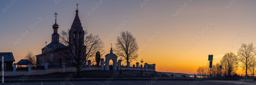 The silhouette of the Orthodox Church against the background of the sunrise. Panoramic view