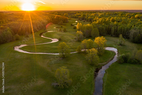 Forest in summer colors. Green deciduous trees and winding blue river in sunset. Mulgi meadow, Estonia, Europe photo