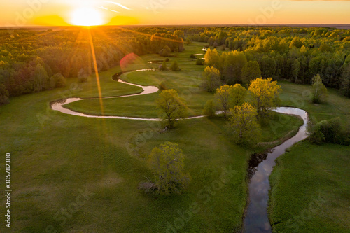 Forest in summer colors. Green deciduous trees and winding blue river in sunset. Mulgi meadow, Estonia, Europe photo