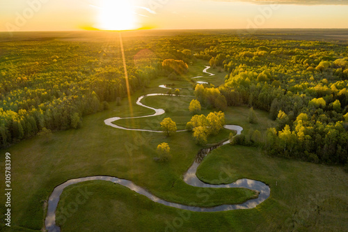 Forest in summer colors. Green deciduous trees and winding blue river in sunset. Mulgi meadow, Estonia, Europe photo