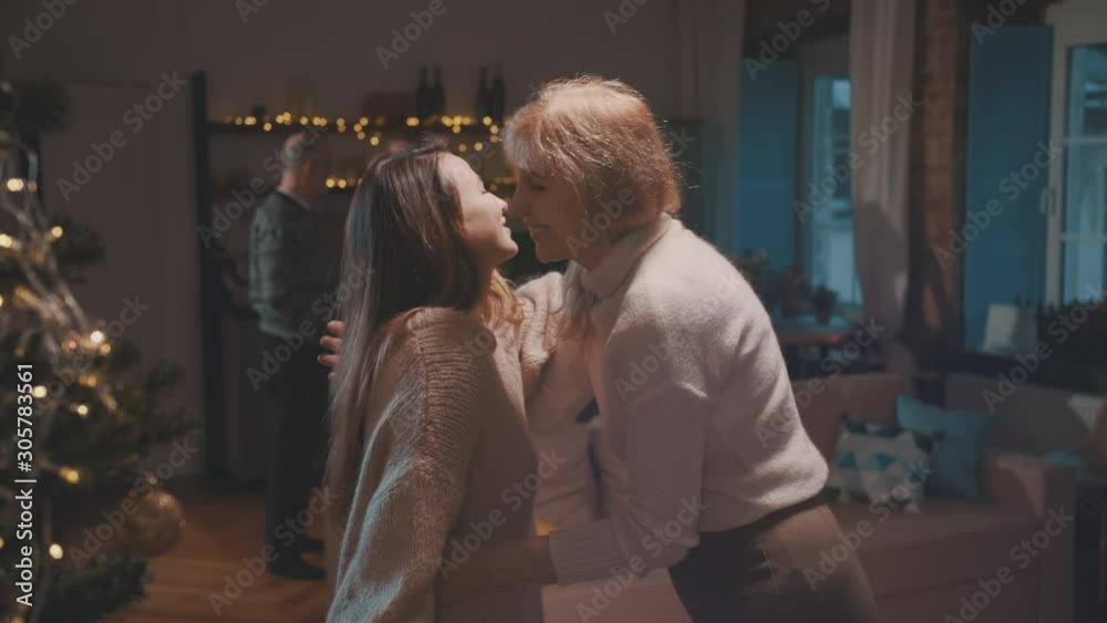 Daughter giving a present to senior mother at home at Christmas time. Daughter giving a present to senior mother at home at Christmas time.