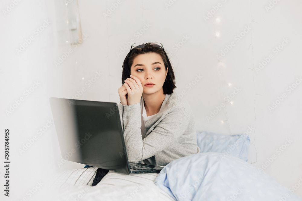 Businesswoman working on her laptop in the white bed. Work at home. Freelancer lifestyle Businesswoman working on her laptop in the white bed. Work at home. Freelancer lifestyle