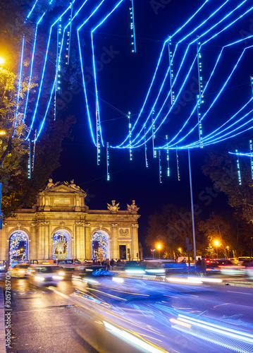 Madrid, Spain - November 25, 2019. Alcala street illuminated by christmas lights at nightfall with the Alcala Gate (Puerta de Alcala) in the background. Madrid, Spain. photo