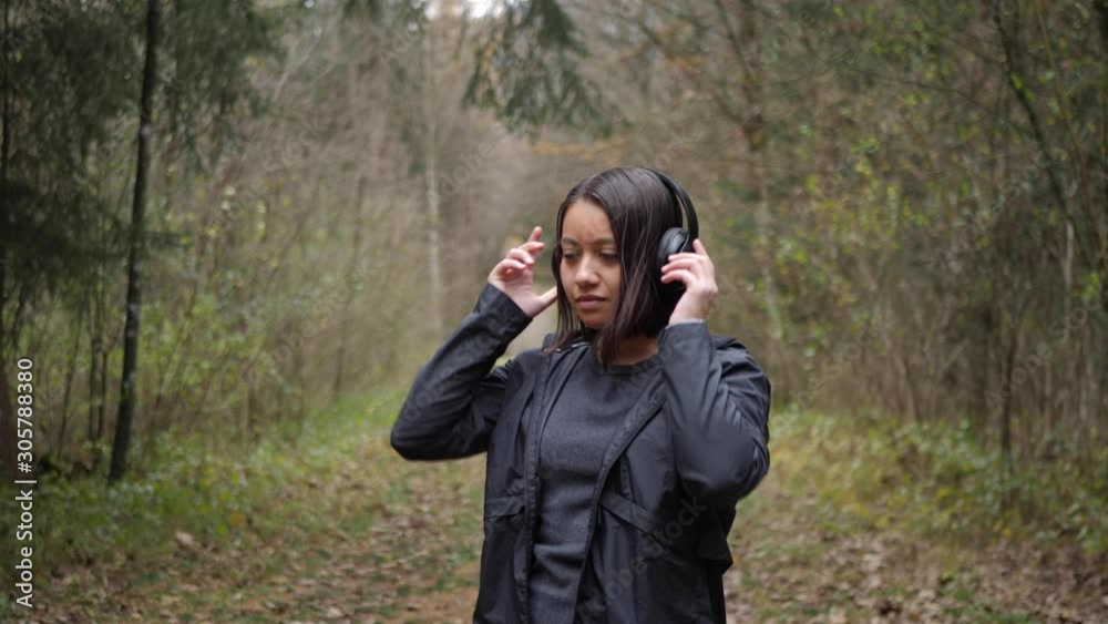 Woman puts on her headphones, activates her fitness app on the smartwatch and starts her run through the forest - Slow Motion Woman puts on her headphones, activates her fitness app on the smartwatch and starts her run through the forest - Slow Motion