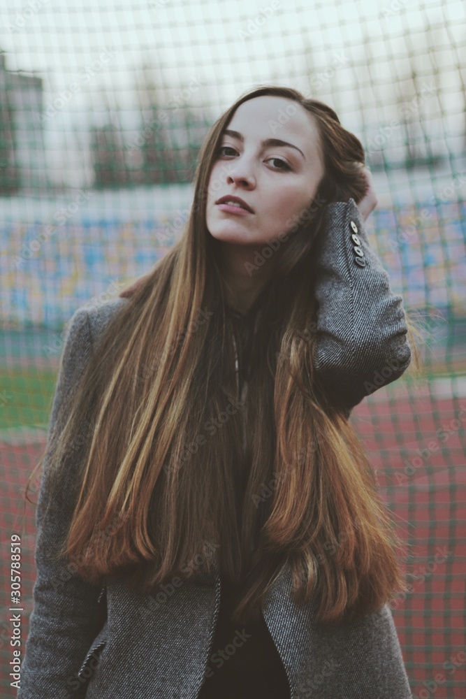 Sensual portrait of beautiful young girl walking in the old abandoned stadium on cold autumn day