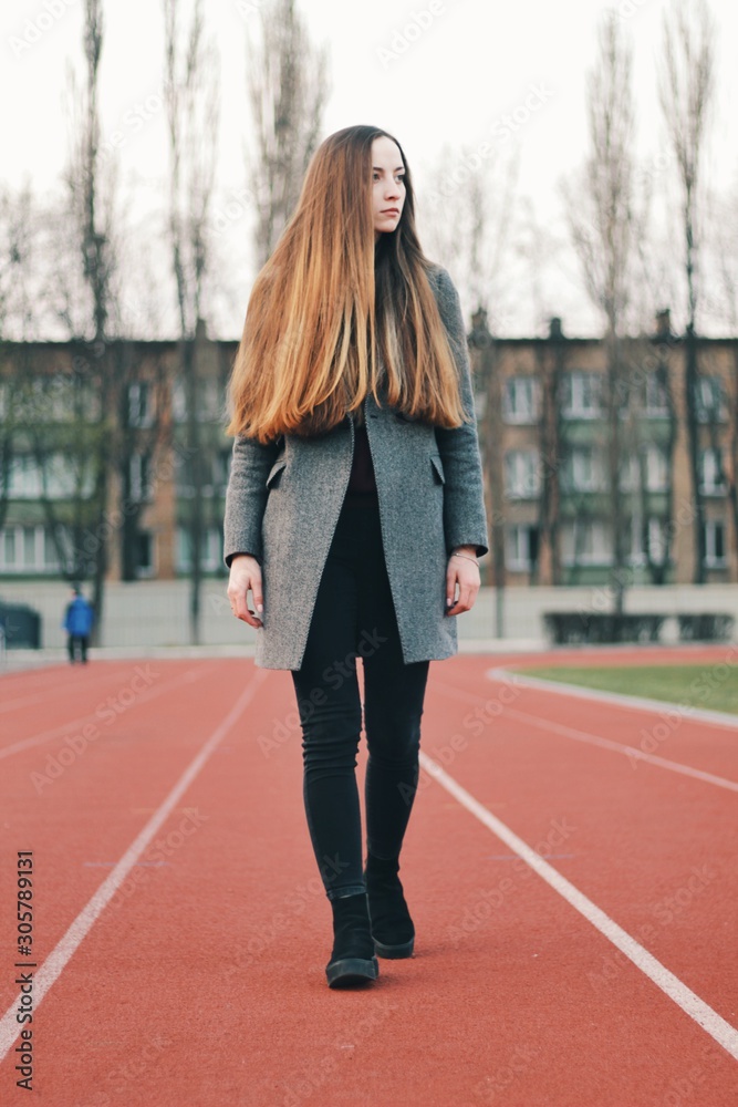 Sensual portrait of beautiful young girl walking in the old abandoned stadium on cold autumn day