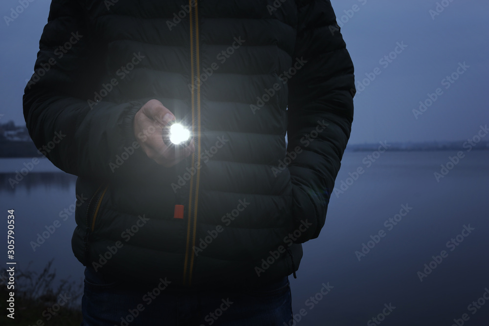 Man with flashlight walking outdoors, closeup view - obrazy, fototapety, plakaty 