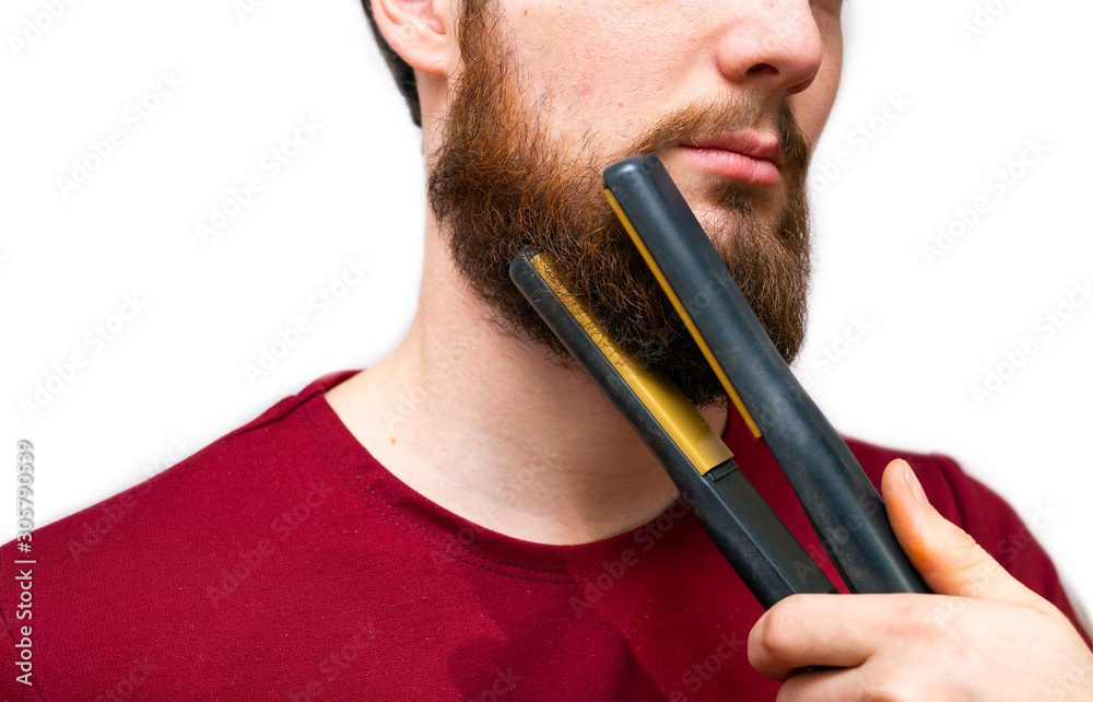 Φωτογραφία Portrait of man straightened his beard with a straightener, styling his beard on