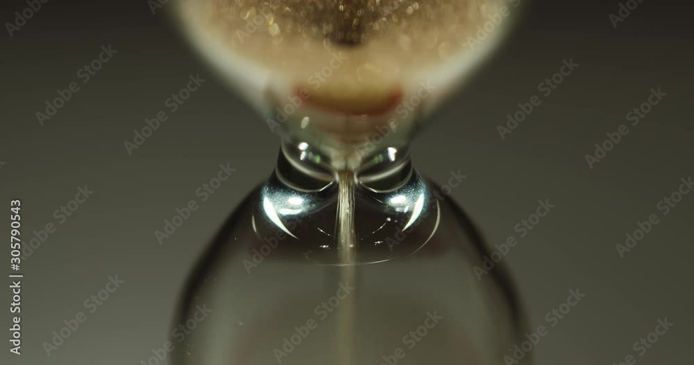 Time is running out. The sand flows slowly through the narrowing of the hourglass Time is running out. The sand flows slowly through the narrowing of the hourglass