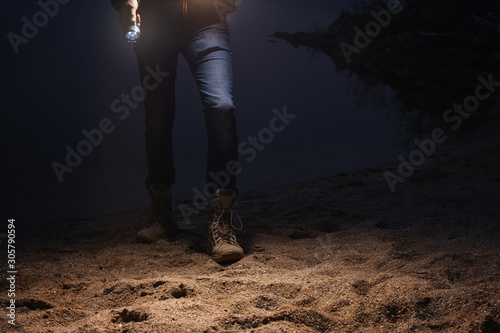 Man with flashlight walking at riverside, closeup