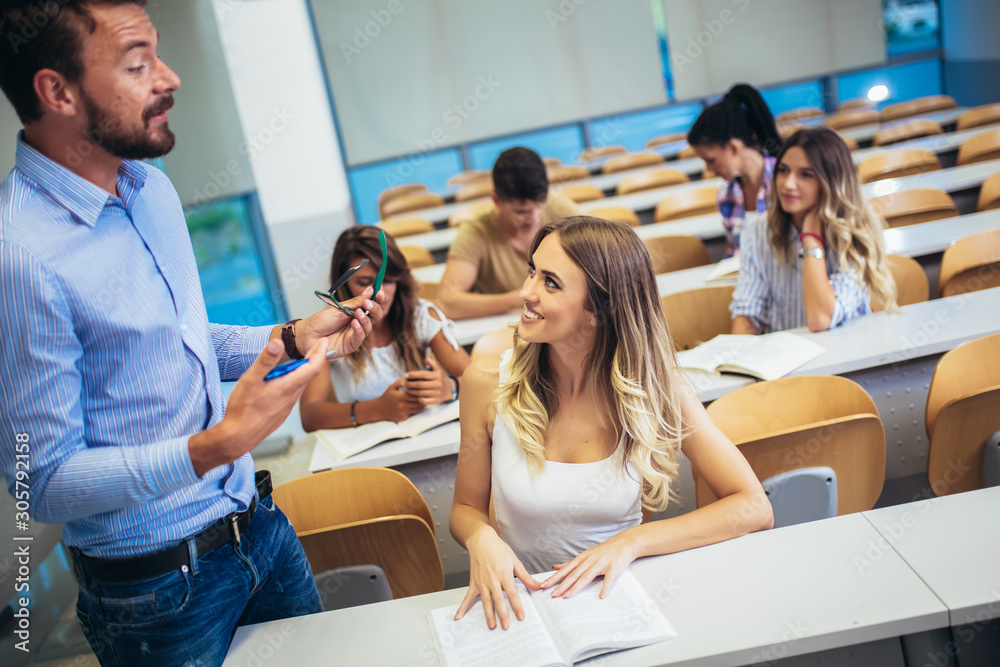 Male tutor teaching university students in classroom.