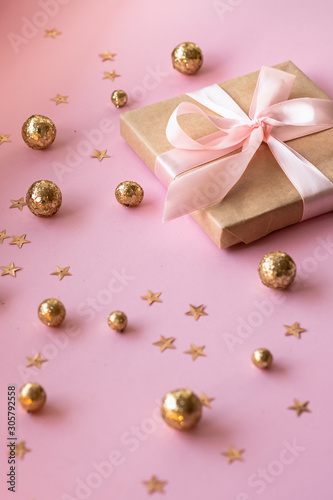 Gift in craft paper with a pink bow on a pink background with gold decorative balls and stars. Template  banner for greeting card your text design 2020. New year, christmas, birthday