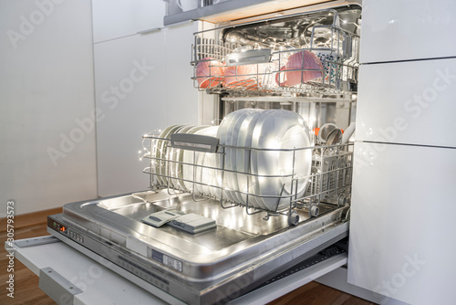 Dishwasher with dishes in kitchen furniture.