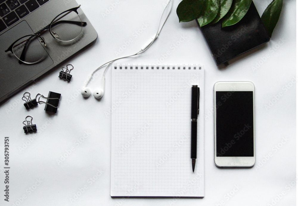 Desk with laptop, eye glasses, pen and smartphone screen. Top view with copy space.