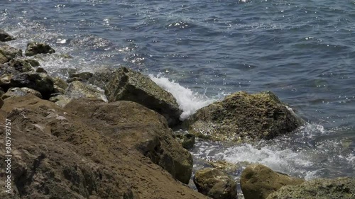 Close up shot of a blue waves of a beautiful sea crushing onto stones of a sea shore. photo