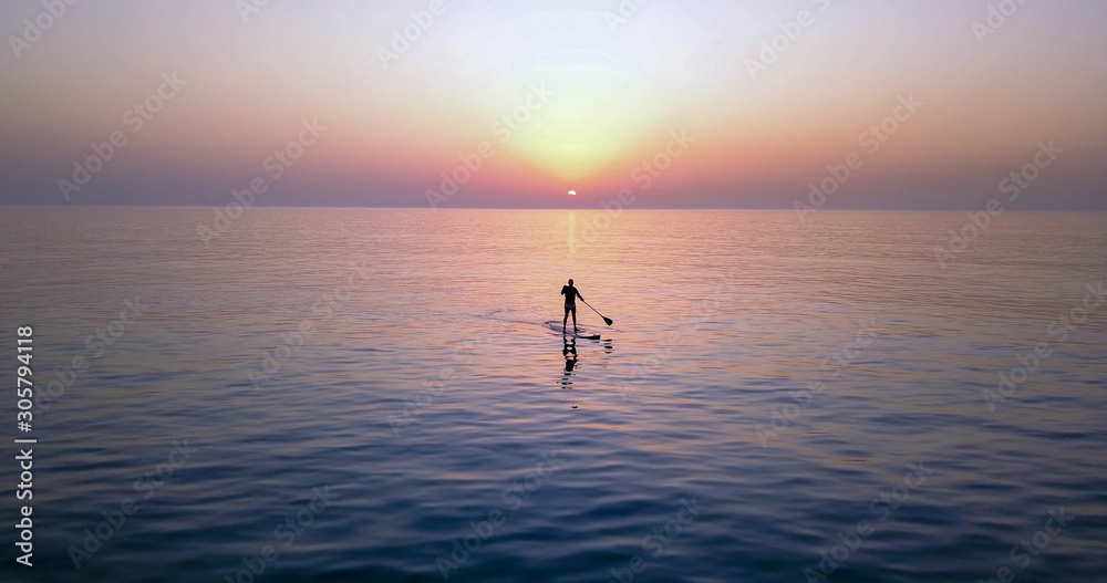 Fototapeta premium SUP Surfing on amazing sea sunset. Image of Stand Up Paddle Board Man Silhouette on Amazing Sunset over Sea. Standup Paddle Boarding.