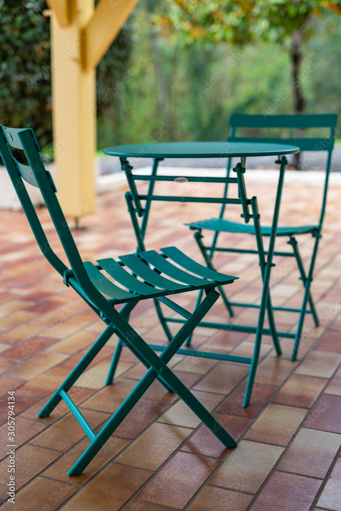Vintage metal green table and two chairs on the terrace of the house