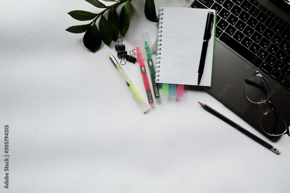 Desk with laptop, eye glasses, pen and smartphone screen. Top view with copy space.