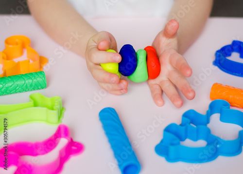 Child hands playing with colorful clay. Homemade plastiline. Plasticine. play dough. Girl molding modeling clay. Homemade clay.