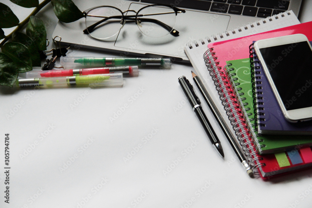 Desk with laptop, eye glasses, pen and workbooks. Top view with copy space.