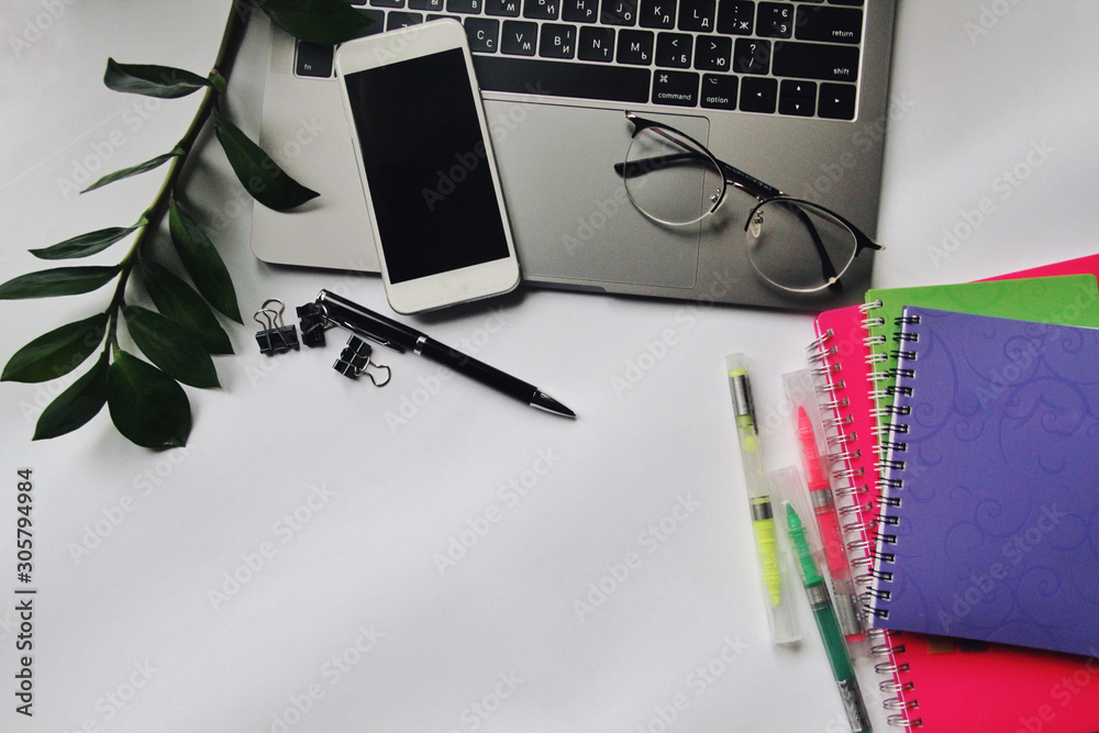 Desk with laptop, eye glasses, pen and smartphone screen. Top view with copy space.