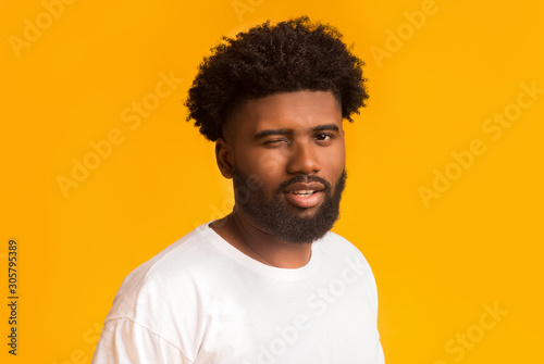 Confident afro guy flirting over orange background