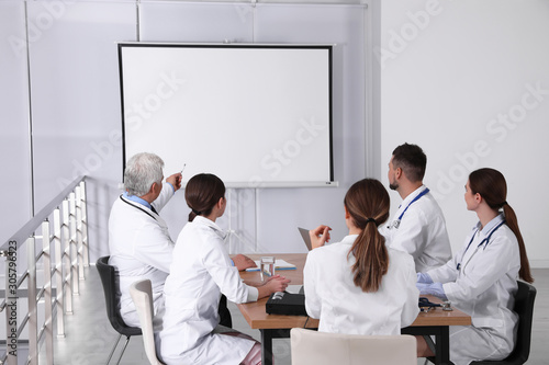 Team of doctors using video projector during conference indoors