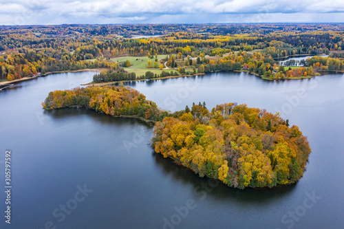 Island in the lake and forest in autumn colors. Golden trees and a blue water, nature environment. Sundown evening light in fall.