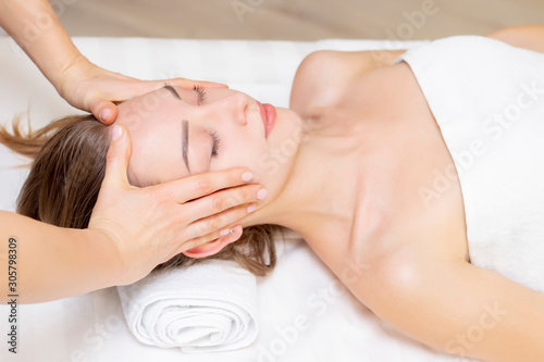 Young woman enjoying massage in spa salon. Face massage. Closeup of young woman getting spa massage treatment at beauty spa salon.Spa skin and body care. Facial beauty treatment.Cosmetology.