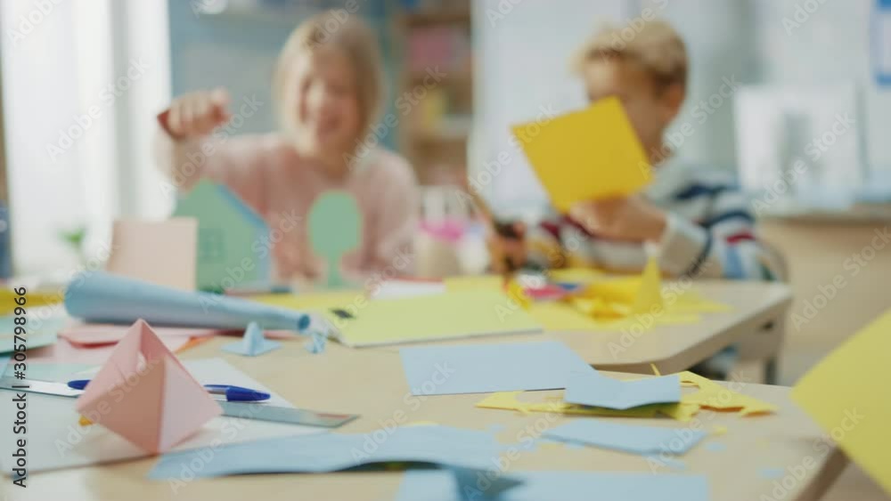 Elementary School Arts & Crafts Class: Diverse Group of Smart Children Have Fun on a Handicraft Project, Using Colorful Paper, Scissors and Glue to Build Papier Mache House. Slow Motion Moving Camera