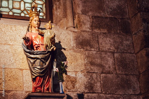 Santiago de Compostela, Spain - 10/13/2018: medieval statue of Our lady with Jesus Christ baby. Saint Mary with Jesus baby filtered. Ancient religious architecture. God Mother with Son stone monument.