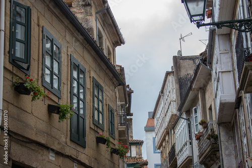 Santiago de Compostela landmark.  Buildings at old medieval street. Camino de Santiago concept. European architecture. Windows, outdoor flowers and lantern at narrow street. Pilgrimage centre.