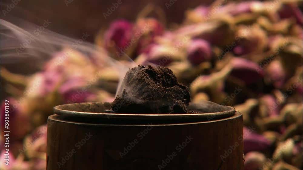 Extreme close-up low-angle still shot of bakhoor or oud incense burning at a market stall, Spice Souk, Creek Dubai, Dubai