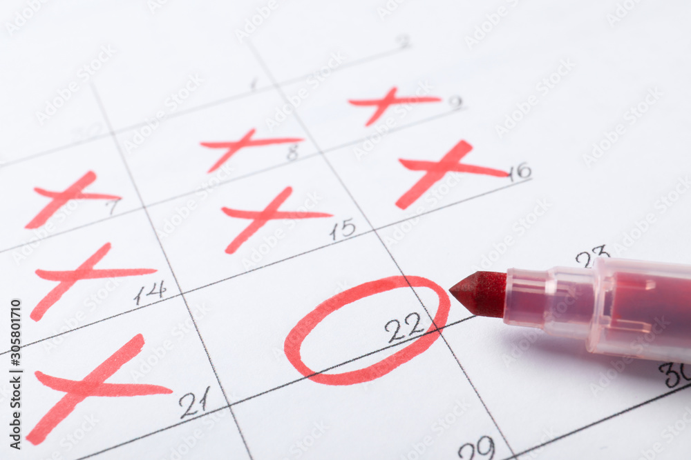 Felt pen on calendar page with marked dates, closeup Felt pen on calendar page with marked dates, closeup