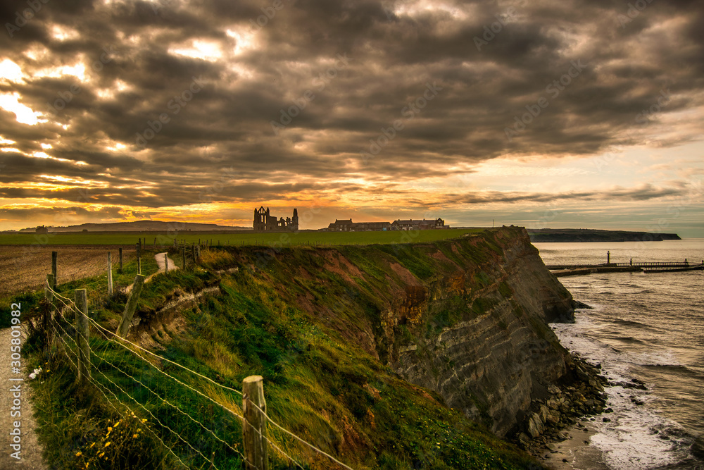 Whitby cliffs sunset. Whitby abbey on the background. 