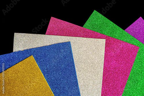 Colored foamiran sheets with sparkles on black background