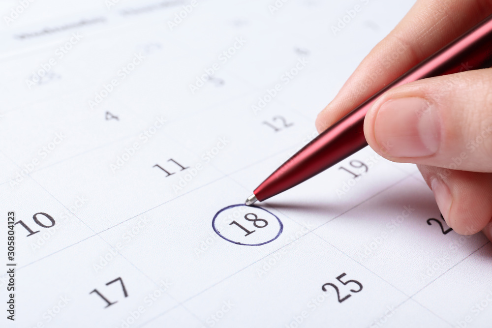 Woman marking date in calendar with pen, closeup Woman marking date in calendar with pen, closeup