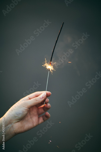 A girl holds a sparkler in her hand. 