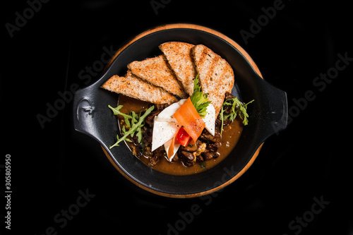 Rustic bowl of cooked beef in sauce, vegetables, decorations and toasted pieces of bread photo